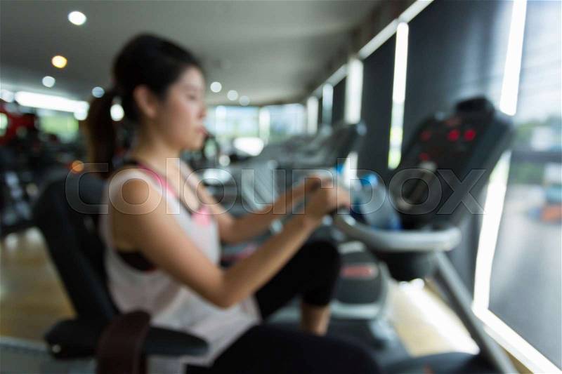 Woman cycling burn fat on bicycle cardio machine in fitness gym exercise sport club center, blurred image used for your background, stock photo