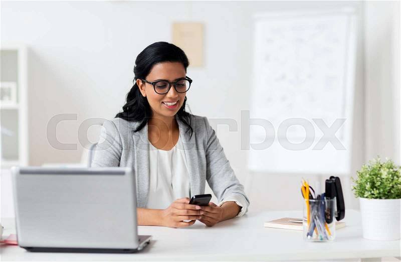 Business, technology, communication and people concept - happy smiling businesswoman with smartphone and laptop at office, stock photo