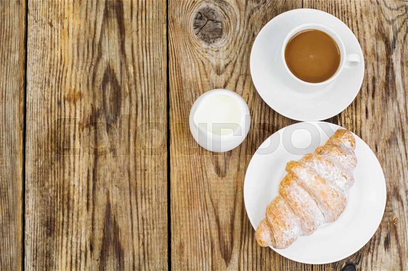 Breakfast. Fresh croissant and cup of coffee with milk on wooden table. Studio Photo , stock photo