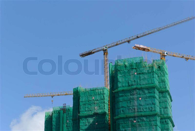 Construction site with crane and building against blue sky, stock photo