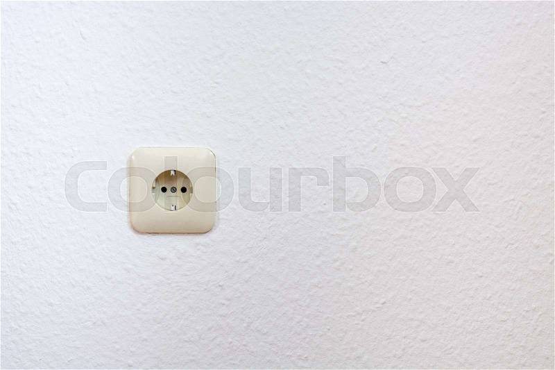 One single european plug on a white wall from the front, stock photo