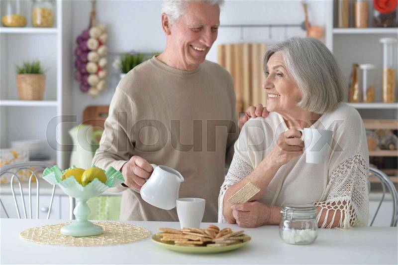 Happy senior couple drinking tea in kitchen, stock photo
