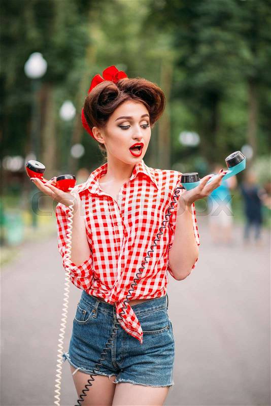 Glamour pin up girl with retro rotary telephones, vintage american fashion. Attractive woman in pinup style, stock photo