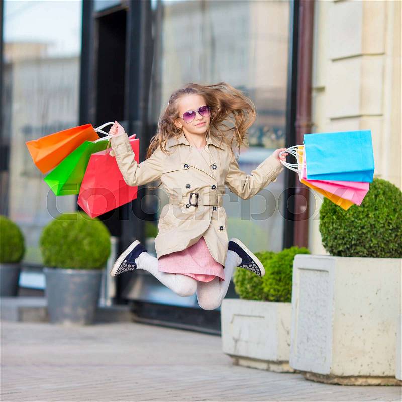 Adorable little girl walking with shopping bags outdoors in Europe. Fashion toddler kid in european city outdoors, stock photo