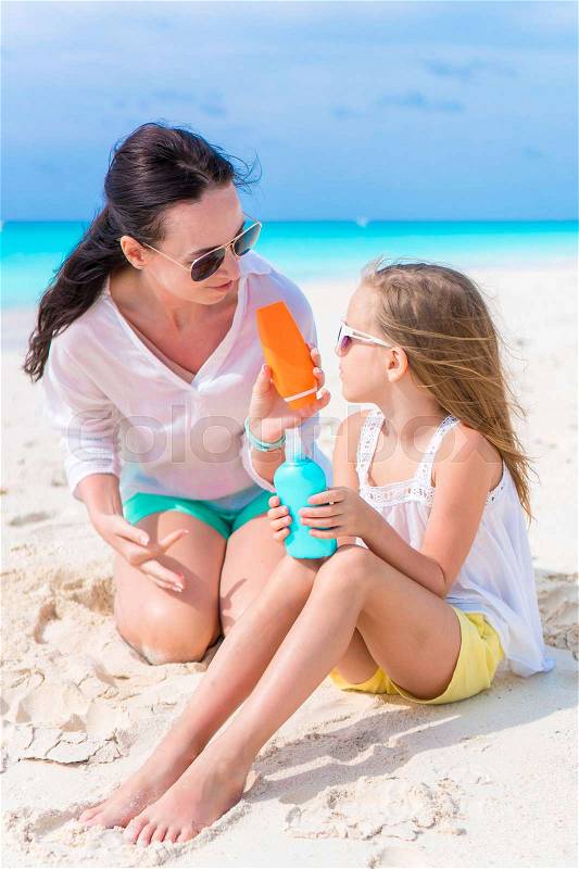Caring mom applying sun cream to kid nose on white beach. The concept of protection from ultraviolet radiation, stock photo