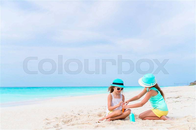 Two caring girls take care of each other on white beach. The concept of protection from ultraviolet radiation, stock photo