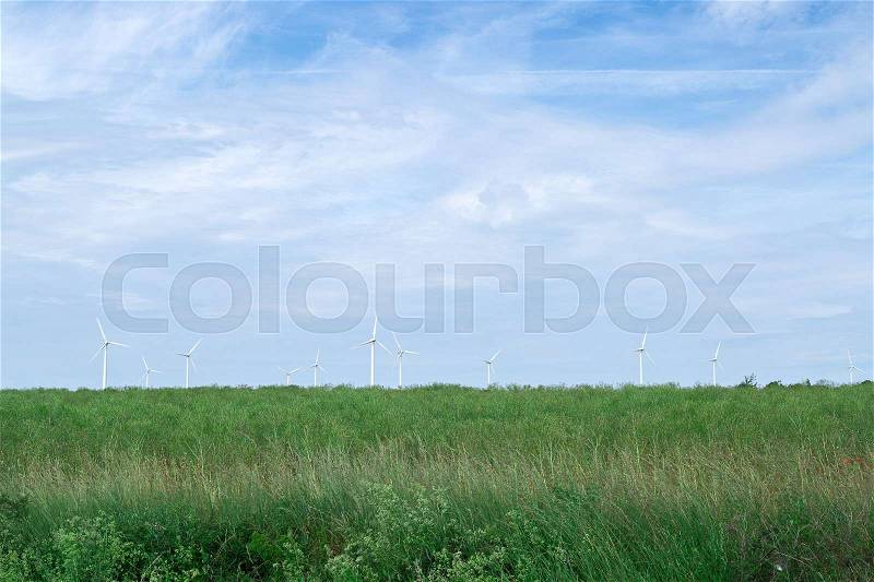 Wind Power Stations in Green Field with a partly cloudy sky, stock photo
