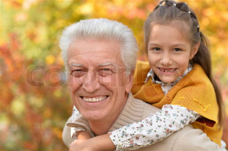 Grandfather and granddaughter having fun in autumnal park, stock photo