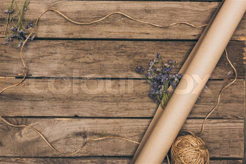 Top view of beautiful dried flowers, craft paper and rope arranged on wooden table, stock photo