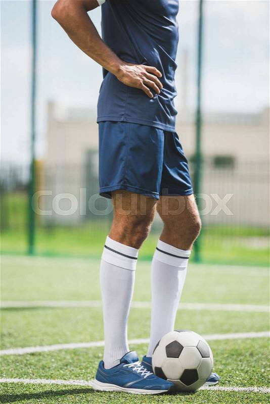 Partial view of soccer player standing on soccer pitch with ball, stock photo