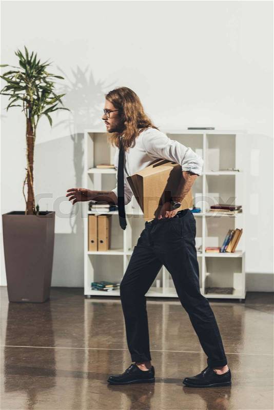 Side view of handsome young businessman holding folders and running in office, stock photo