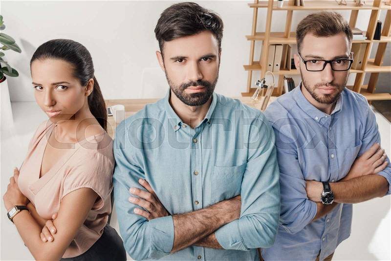High angle view of serious business people with crossed arms standing at workplace in office, stock photo
