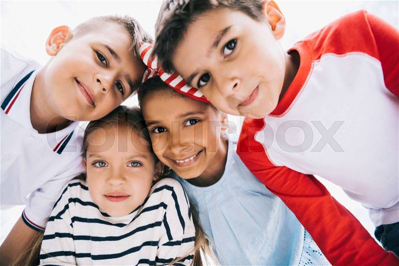 Close-up portrait of happy multiethnic kids standing together and smiling at camera, stock photo