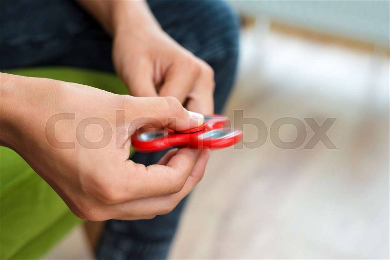 Fidget spinner. Red hand spinner, fidgeting hand toy rotating on child\'s hand. Stress relief. Anti stress and relaxation adhd attention fad boy concept, stock photo