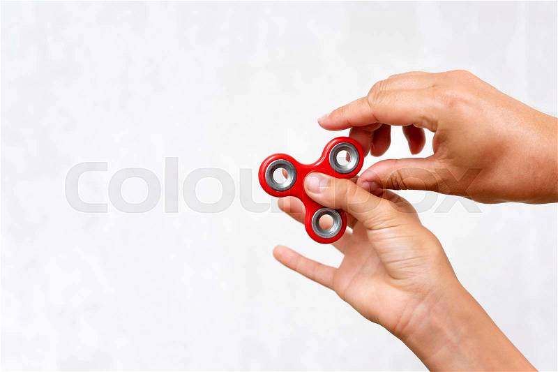 Fidget spinner. Red hand spinner, boys playing with fidgeting hand toy. Stress relief. Anti stress and relaxation adhd attention fad boy concept. Free space for text, stock photo