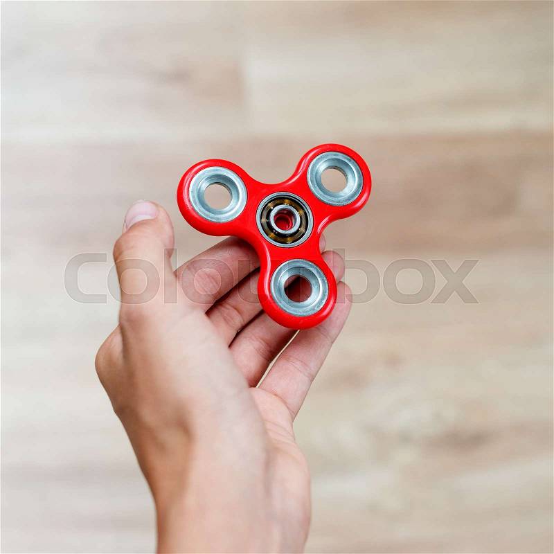 Fidget spinner. Red hand spinner, fidgeting hand toy rotating on child\'s hand. Stress relief. Anti stress and relaxation adhd attention fad boy concept, stock photo