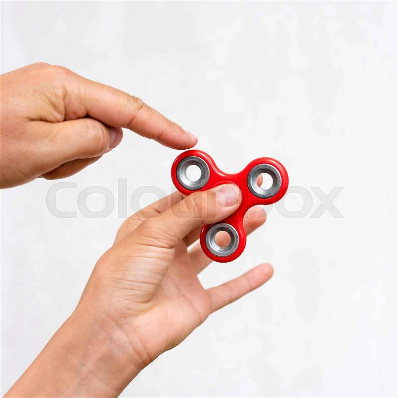 Fidget spinner. Red hand spinner, boys playing with fidgeting hand toy. Stress relief. Anti stress and relaxation adhd attention fad boy concept, stock photo