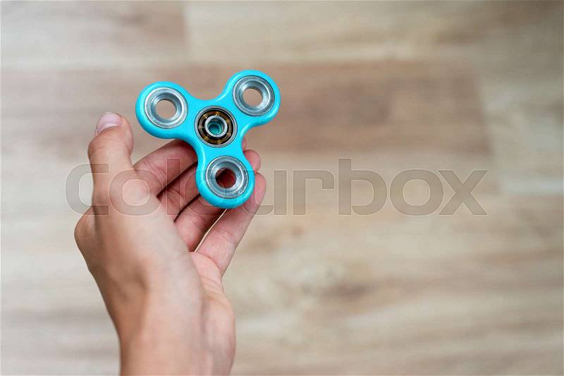 Fidget spinner. Blue hand spinner, fidgeting hand toy rotating on child\'s hand. Stress relief. Anti stress and relaxation adhd attention fad boy concept. Free space for text, stock photo