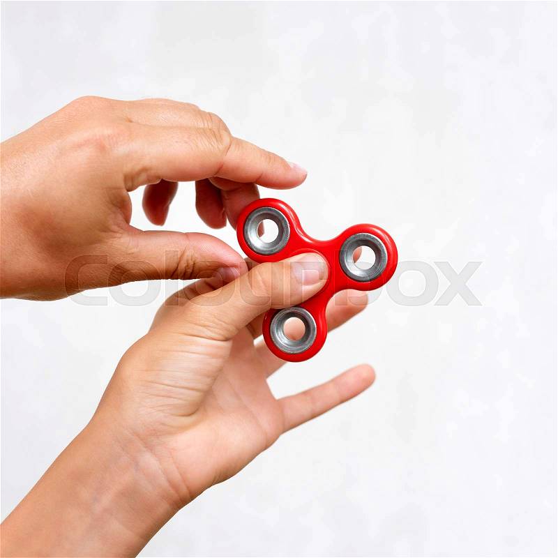 Fidget spinner. Red hand spinner, boys playing with fidgeting hand toy. Stress relief. Anti stress and relaxation adhd attention fad boy concept, stock photo