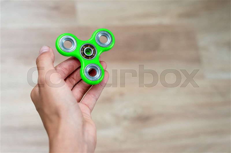 Fidget spinner. Green hand spinner, fidgeting hand toy rotating on child\'s hand. Stress relief. Anti stress and relaxation adhd attention fad boy concept. Free space for text, stock photo
