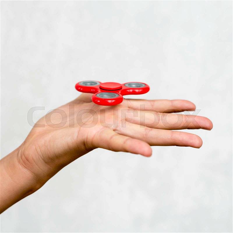 Red hand spinner. Boy playing a popular toy fidget spinner in his hand. Stress relief. Anti stress and relaxation adhd attention fad boy concept, stock photo