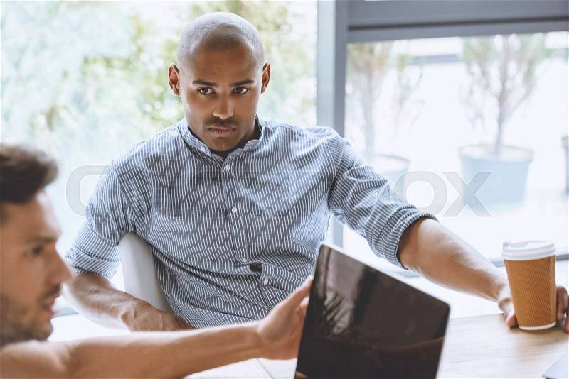 Portrait of focused african american businessman listening to colleague at business meeting, stock photo