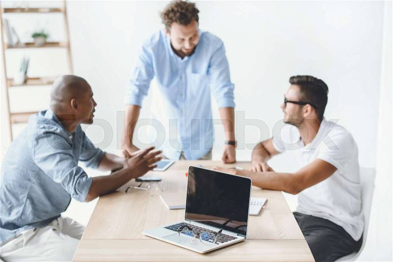 Multiethnic businessmen discussing new business idea at workplace on meeting, stock photo