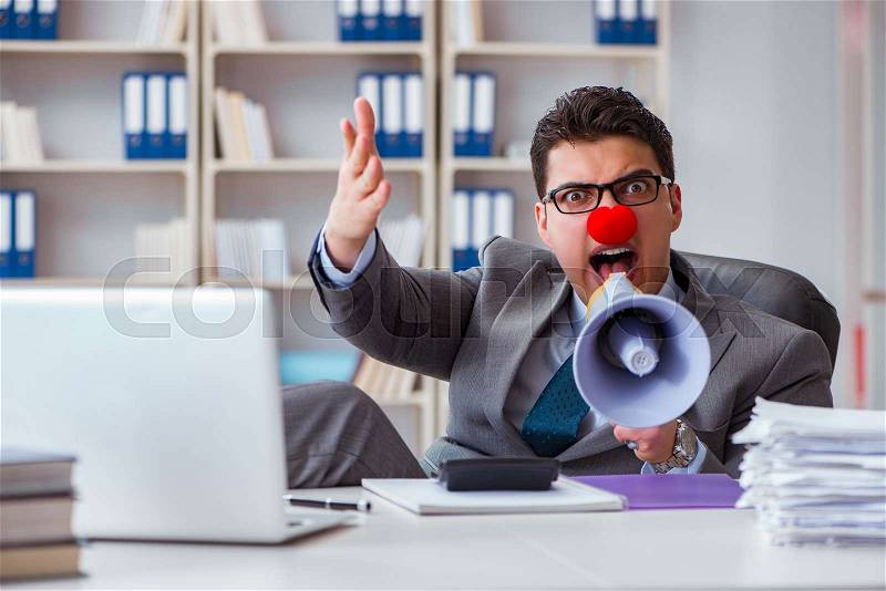 Clown businessman angry in the office with a megaphone, stock photo