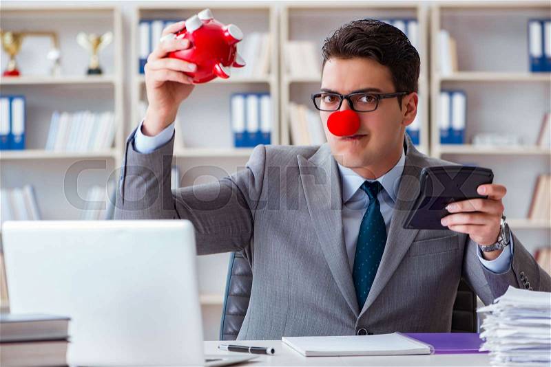 Clown businessman with piggy bank doing accounting, stock photo