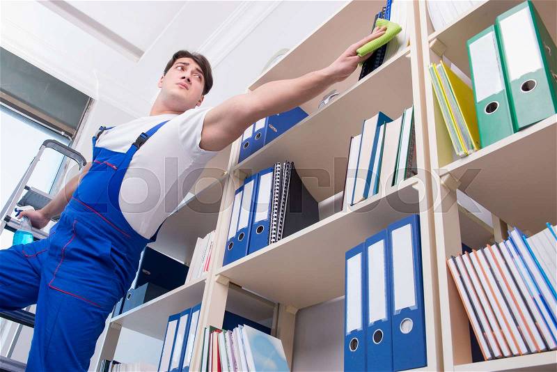 Male office cleaner cleaning shelves in office, stock photo