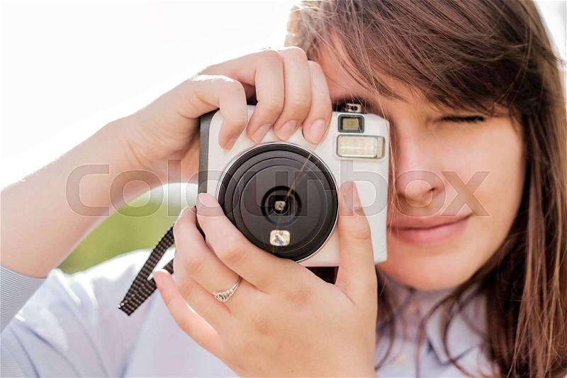 Lovely young long-haired girl with instant camera. She looks at you and smiles, stock photo