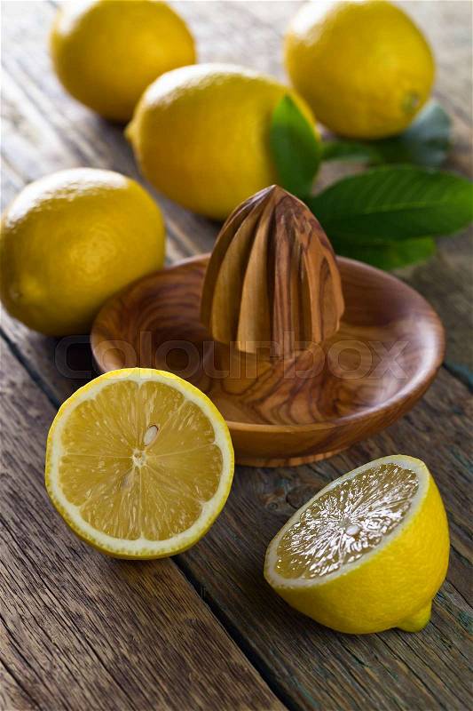 Ripe lemons and squeezer on a old wooden table , stock photo
