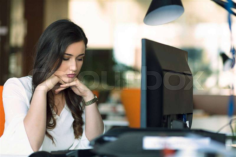 Young tired business woman with headache sitting in workplace, stock photo