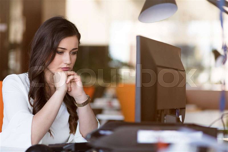 Young tired business woman with headache sitting in workplace, stock photo