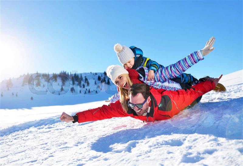 Happy young family playing in fresh snow at beautiful sunny winter day outdoor in nature, stock photo