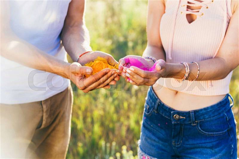 Cropped shot of couple holding colorful powder in hands at holi festival, stock photo