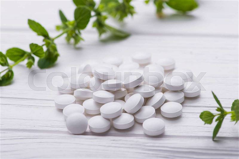 Natural organic pills with herbal plant on white wood table. ethnoscience concept, stock photo