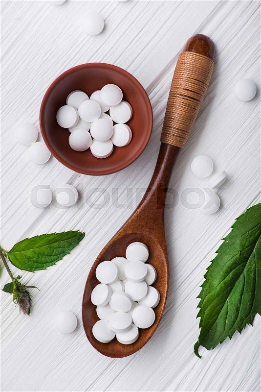Natural organic pills with herbal plant on white wood table. ethnoscience concept, stock photo