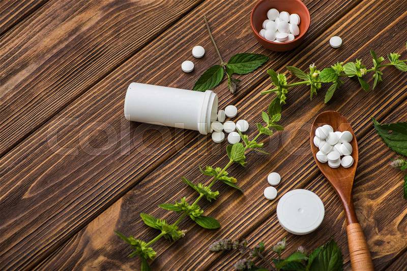 Natural organic pills with herbal plant on wood table. ethnoscience concept, stock photo