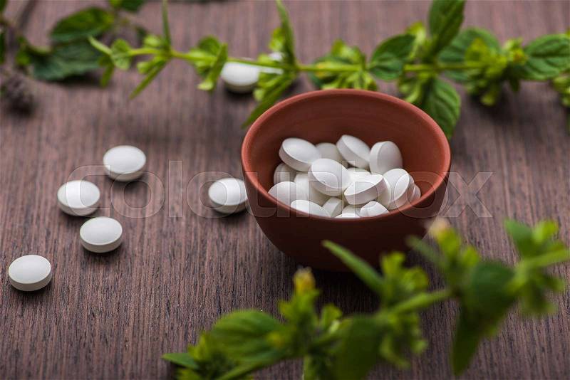 Organic medical pills with herbal plant on wood table. ethnoscience concept, stock photo