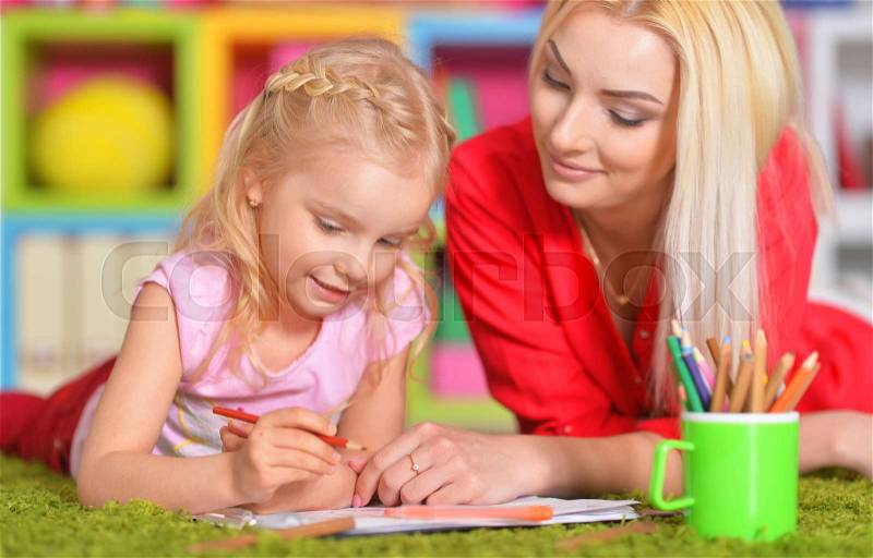 Happy mother draws with her little daughter, stock photo