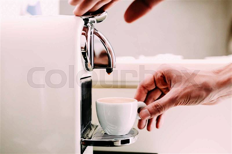 Close up of hand of barista brewing coffee using a coffee machine. Man's hand with a cup of fresh coffee with foam, stock photo