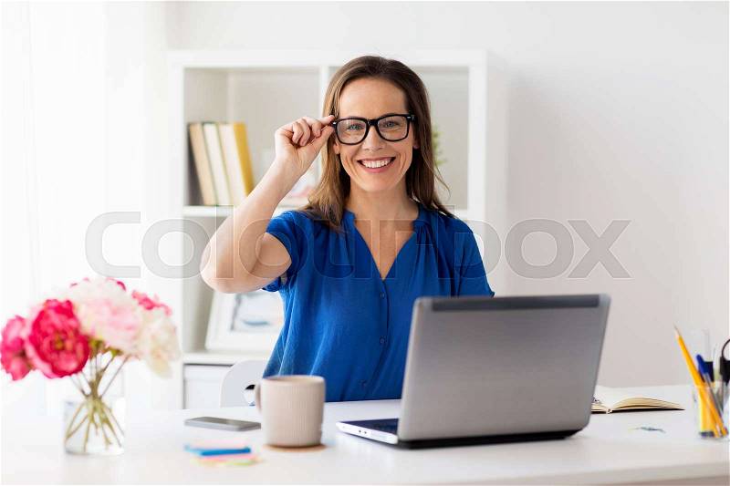 Business, vision and people concept - happy smiling woman with laptop computer working at home or office, stock photo