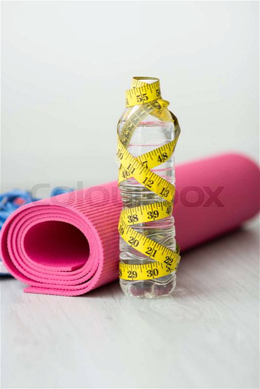 Yoga mat, bottle of water and centimeter on wooden background. Sport equipment. Concept healthy life. Selective focus, stock photo