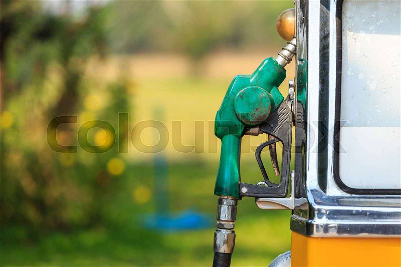 Old of green fuel nozzle in gas station on green blur background, stock photo