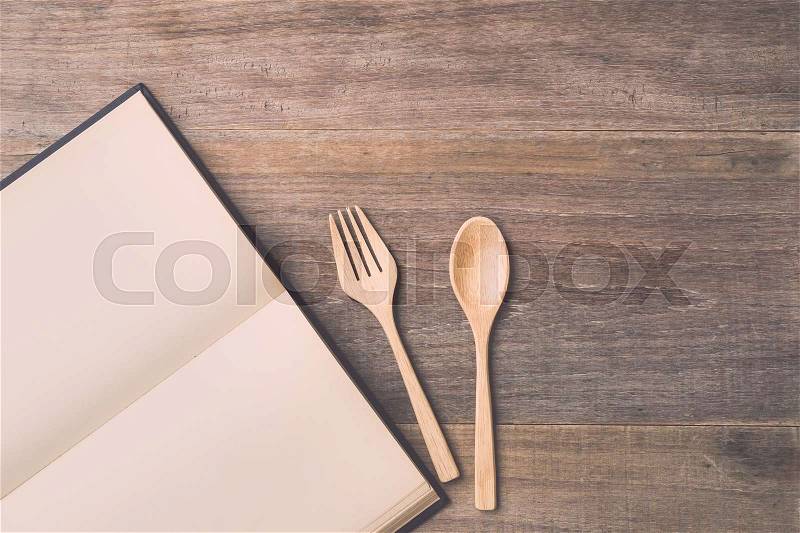Top view spoon, fork and book on wooden plank background. Eating knowledge concept, stock photo