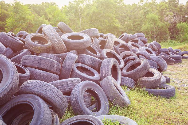 Stack of old rubber car tire in green grass field. Use for environment concept, stock photo
