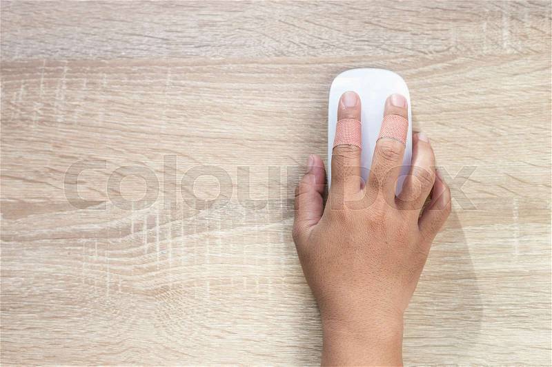 Top view hand with injury on finger using white computer wireless mouse on wooden background, stock photo