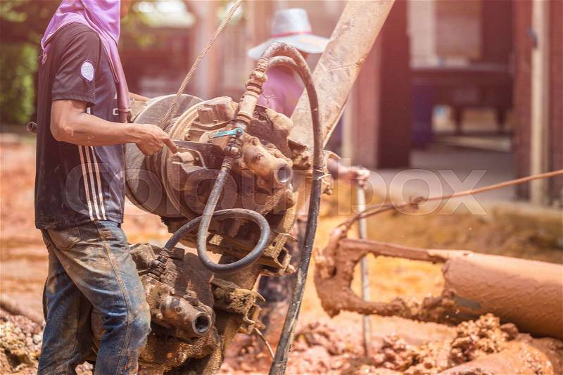 Asian worker installing wet-process bored pile for outside public construction, stock photo