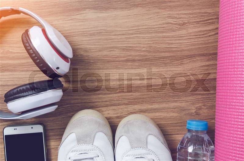 Sport shoes bottle of water, headphone, yoga mat and smart phone on wooden background and copy space for text, stock photo